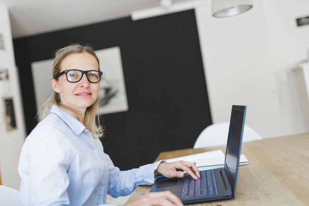 pretty young businesswoman with blue shirt and glasses working in home office - Photo, image