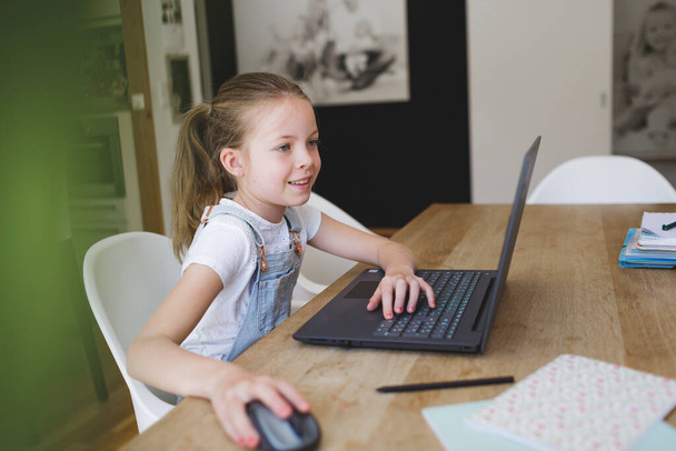 girl working on her laptop during home schooling during corona crisis - 写真・画像