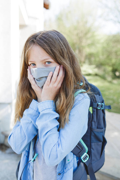 pretty girl with nose mouth mask goes to school after the corona quarantine - Foto, Imagen