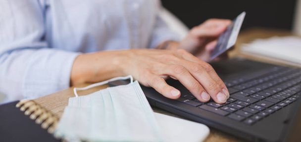cropped shot of business woman doing home shopping with her laptop and credit card on the kitchen table - Foto, afbeelding