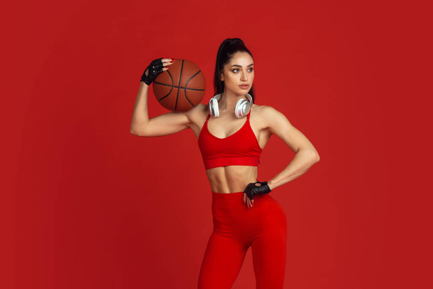 Beautiful young female athlete practicing on red studio background, monochrome portrait - Fotografie, Obrázek
