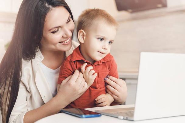 Nő és kisfia webes videóhívást folytat boldog családdal otthon a számítógépen. Kommunikációs emberek fogalma - Fotó, kép