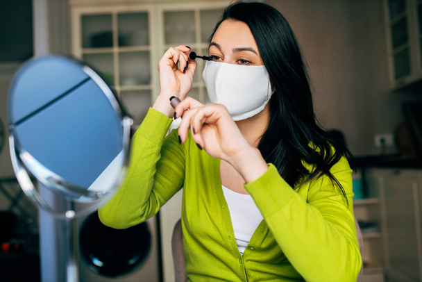 Caucasian woman blogger beautician creating new content for her blog on social networks wearing medical mask. Woman making make-up for her beauty blog on cosmetics. Modern technology, blogging - 写真・画像