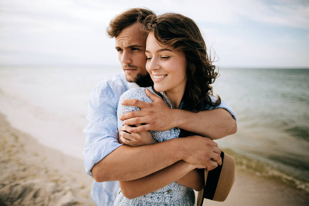 Young man hugging happy woman. Happy couple relaxing at sea in their honeymoon - Photo, image