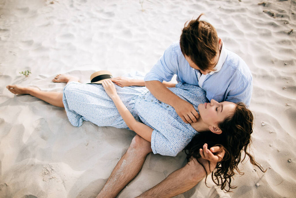 Young couple lying on sea beach kissing and hugging - 写真・画像