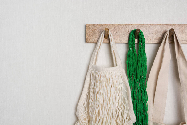 Cotton and mesh green eco bags hang on hanger on wall. Ready for shopping. Copy space. - Valokuva, kuva
