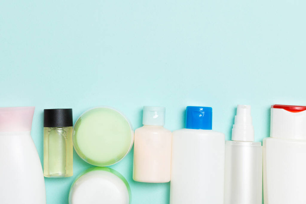 Flat lay composition with cosmetic and cream bottles on blue background. Beauty products concept with copy space. - Фото, зображення