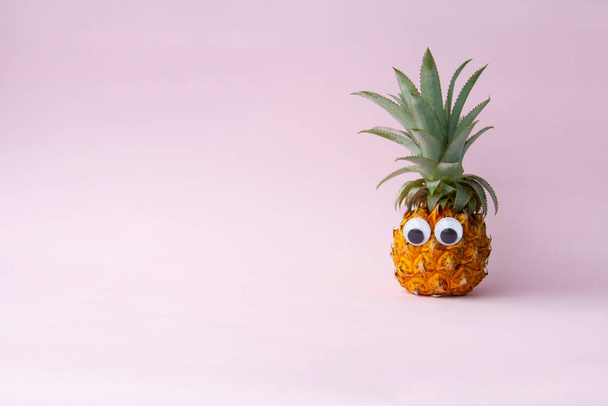 Fresh funny pineapple with googly eyes on pink background, copy space - Photo, image
