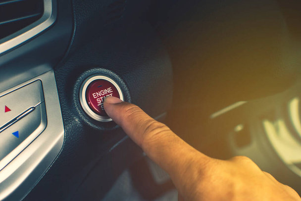 Dłoń kierowcy samochodu naciśnij przycisk Start / Stop silnika do zapłonu silnika w luksusowym samochodzie. - Zdjęcie, obraz