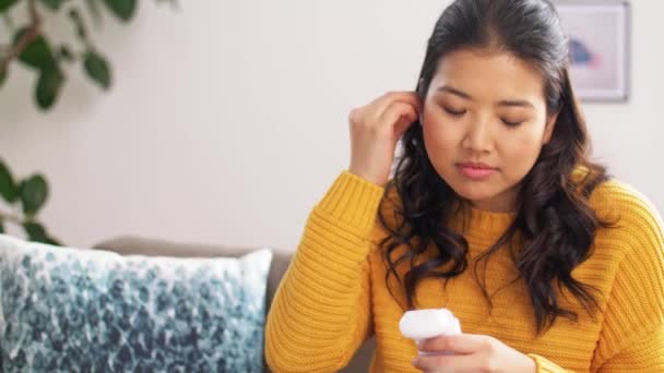 asian woman with earphones and smartphone at home - Filmmaterial, Video