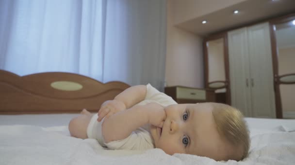 Kék szemű kisgyermek, az ágyon fekvő szőke hajjal - Felvétel, videó