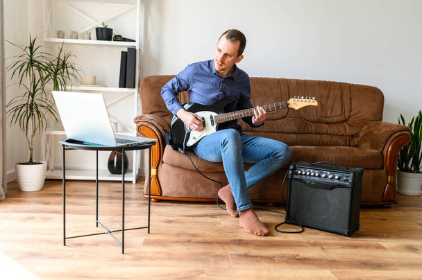 Man is shows how to play electric guitar - Foto, afbeelding