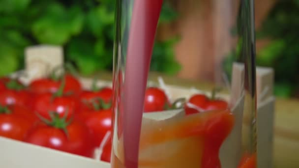 Tomatensaft wird in einen Glaskrug neben der Holzkiste voller Tomaten gegossen - Filmmaterial, Video