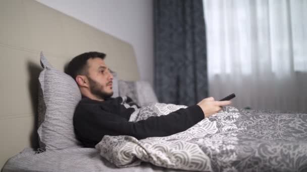 Homem deitado na cama, mudando de canal com controle remoto
 - Filmagem, Vídeo