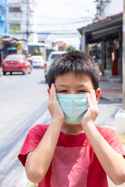 Рука с маской на лице азиатского мальчика на улице в Бангкоке, Таиланд
. - Фото, изображение
