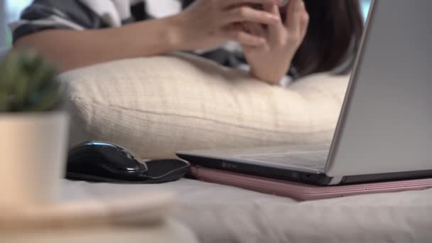 Aasialainen nuori nainen työskentelee kotona, tyttö käyttää kannettavaa tietokonetta makaa sängyssä kotona, harrastus, teknologia ja vapaa-aika, kodin karanteeni elämäntapa aikana covid-19 pysyä kotona koko päivän. rentoutua iloinen ja hauska
 - Materiaali, video