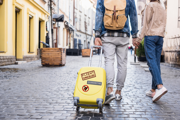Καλλιεργημένη άποψη του ζεύγους περπάτημα με ταξιδιωτική τσάντα στο δρόμο, καραντίνα εικονογράφηση - Φωτογραφία, εικόνα