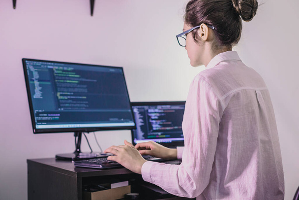 Het programmeur meisje werkt op de computer. Informatietechnologie door de handen van vrouwen. Vrouwen in het bedrijfsleven. Het meisje werkt vanuit huis.. - Foto, afbeelding