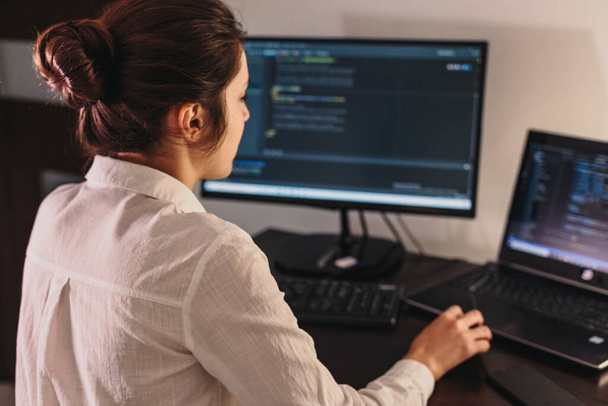 A programozó lány a számítógépnél dolgozik. Információs technológia a nők kezei által. Nők az üzletben. A lány otthonról dolgozik.. - Fotó, kép