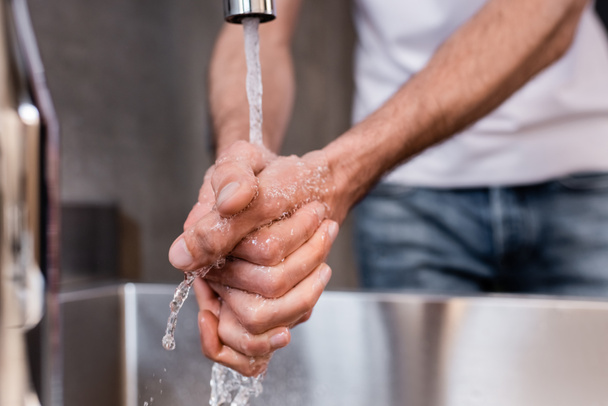 Selective focus of man washing hands at home - Photo, Image