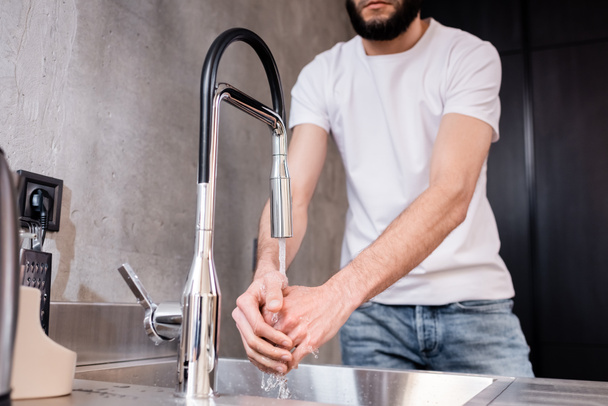 Cropped view of man washing hands in kitchen  - 写真・画像