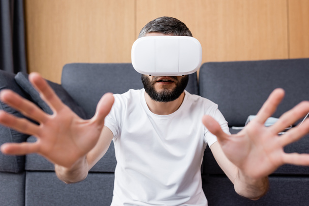 Selective focus of man using vr headset in living room - Foto, afbeelding
