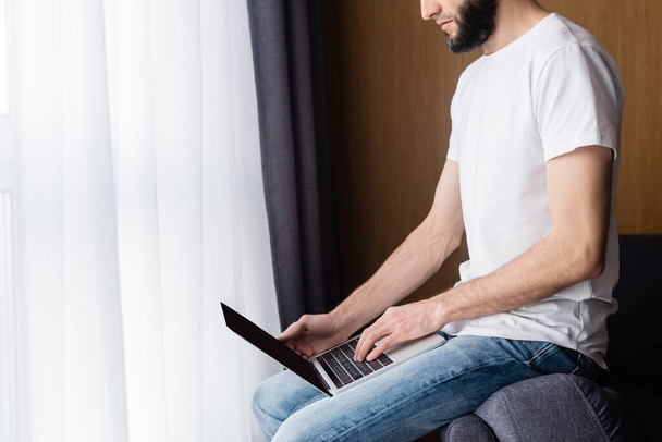 Cropped view of freelancer using laptop in living room - Photo, Image