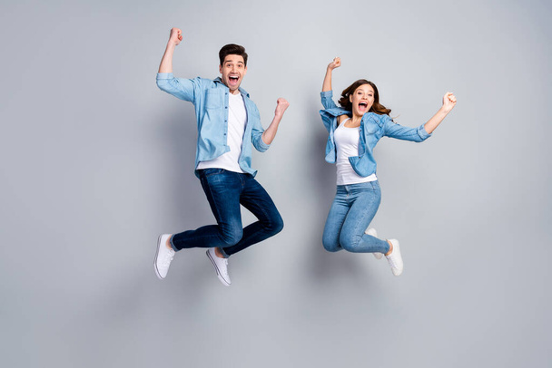 Full body photo of attractive lady handsome funny guy crazy fan jumping high up celebrating football team winning wear casual denim shirts outfit isolated grey color background - Фото, изображение