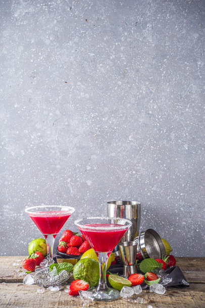 Boisson d'alcool froid d'été. Cocktail de margarita aux fraises, citron vert, menthe et fraise fraîche sur fond bois rustique - Photo, image