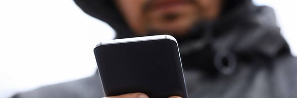 Close-up uomo in cappuccio guarda smartphone display
 - Foto, immagini
