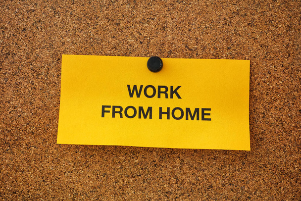 Work From Home written on a yellow piece of paper that is on a bulletin board. Remote work concept. Close up. - Fotó, kép