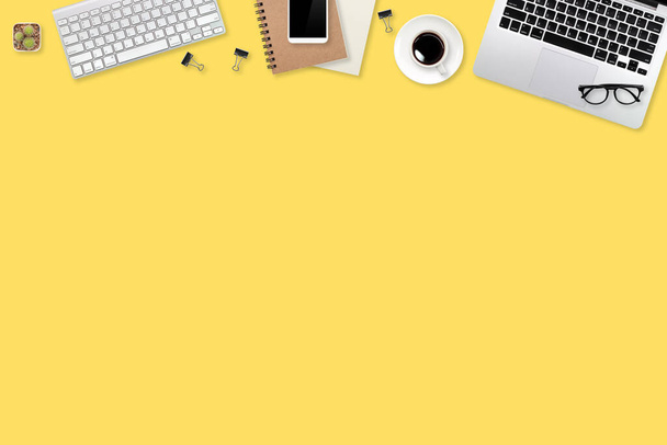 flat lay workspace table with laptop computer, office supplies, coffee cup, tablet and cell phone on yellow pastel background - Photo, Image