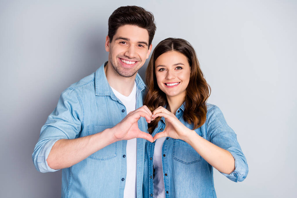 Photo pretty lady handsome guy couple in love making fingers hands heart figure celebrate anniversary valentine day lovers wear casual denim shirts outfit isolated grey color background - Foto, afbeelding