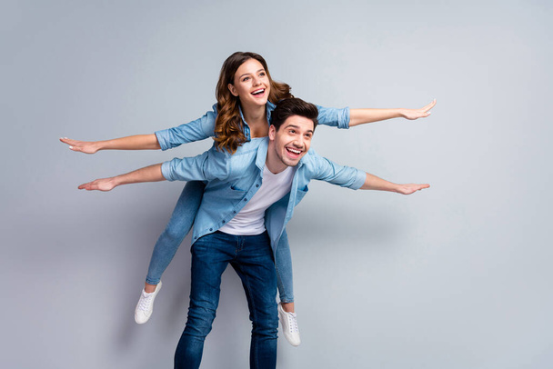 I will show you sky. Portrait of positive cheerful man hold his girlfriend piggyback imagine fly like airplane wear casual style clothes isolated over gray color background - Fotó, kép