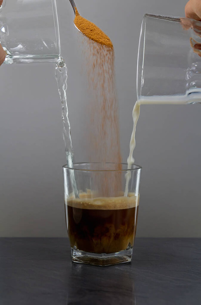 Coffee milk and water mix in small glass on stone desk - Фото, зображення