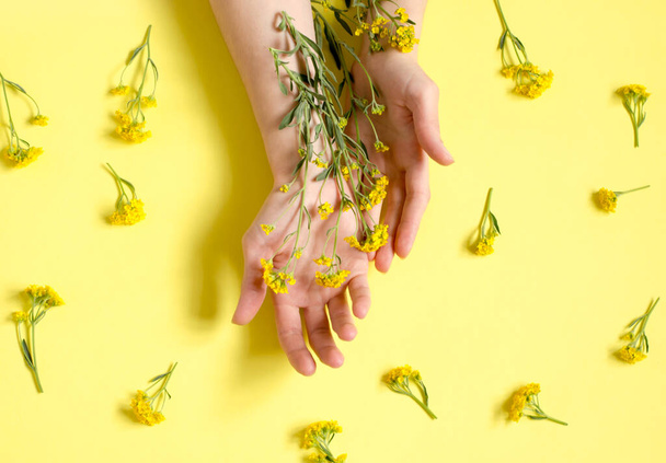 Fashion art portrait woman and bright flowers in her hand. Creative beauty photo girls sitting at table on a contrasting yellow background with colored shadows - Фото, зображення