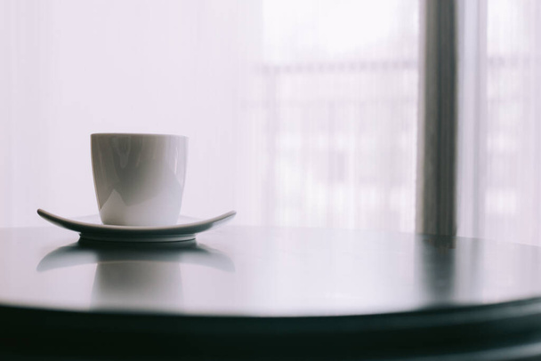 Чашка черного кофе, газета и ручка у окна утром
 - Фото, изображение