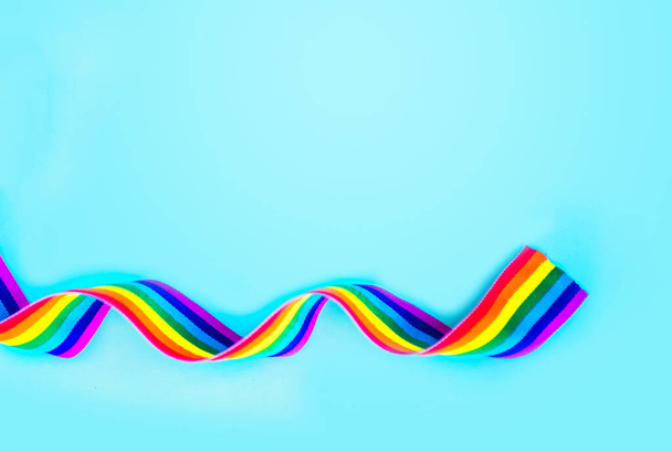 Fita de arco-íris LGBT em um fundo azul. Símbolo da fita do orgulho. Espaço de cópia para texto
 - Foto, Imagem
