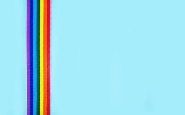 Cinta arco iris LGBT sobre un fondo azul. Símbolo de cinta de orgullo. Copiar espacio para texto
 - Foto, imagen