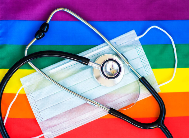 Stethoscoop en medisch masker op de regenboogvlag, LGBT symbool - Foto, afbeelding