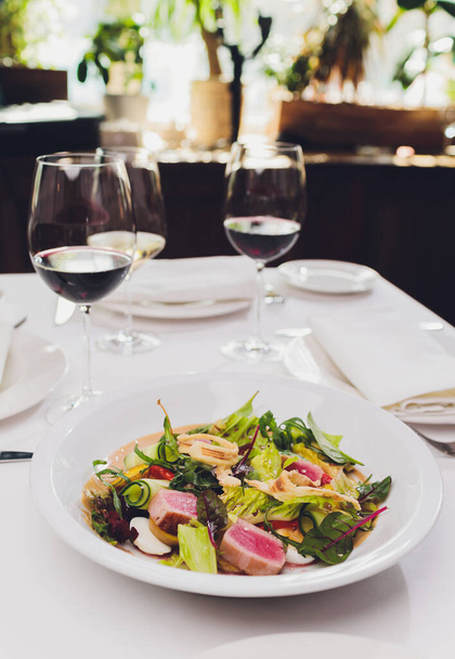 Seared tuna coated sesame seeds with green salad on white plate. - Zdjęcie, obraz