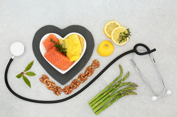 Здорове серцеве харчування для низького рівня холестерину з морепродуктами, фруктами, овочами, горіхами та стетоскопом. Продукти з високим вмістом клітковини, антиоксидантів, вітамінів, омега-3 та білків. Підтримка серцево судинної системи
.  - Фото, зображення