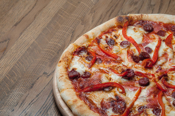 pizza on a wooden tray stands on a wooden table - Foto, Imagen