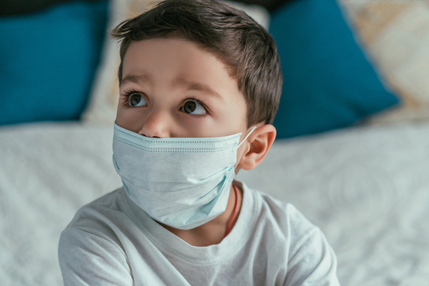 rozkošný batole chlapec v lékařské masce dívá pryč na domov - Fotografie, Obrázek
