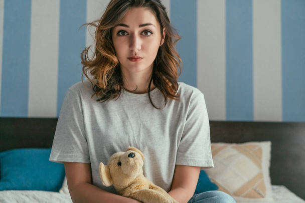 attractive woman looking at camera while holding soft toy at home  - Photo, Image