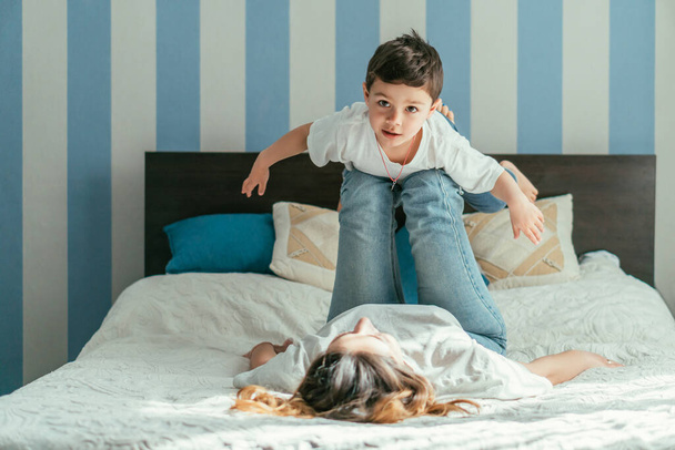 selektywne skupienie się na chłopcu z wyciągniętymi rękami leżącym na nogach matki w sypialni  - Zdjęcie, obraz