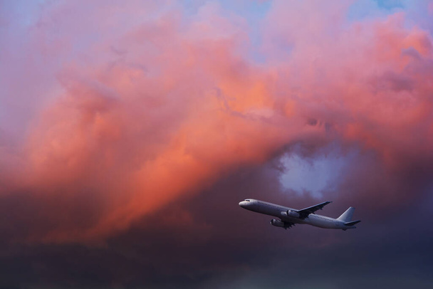 Commercial airplane flying through clouds in dramatic sunset light. Travel concept - Valokuva, kuva
