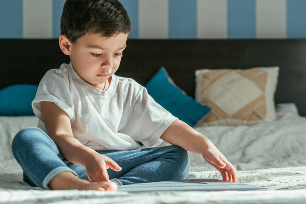 selective focus of cute toddler boy touching laptop in bedroom  - Photo, Image