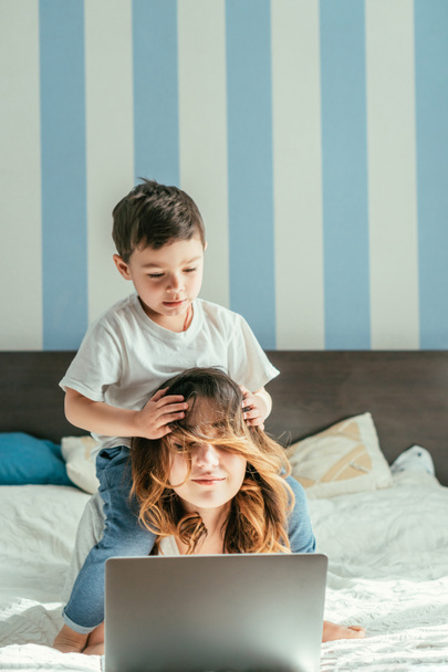 tout-petit garçon toucher les cheveux de la mère pigiste dans la chambre
  - Photo, image