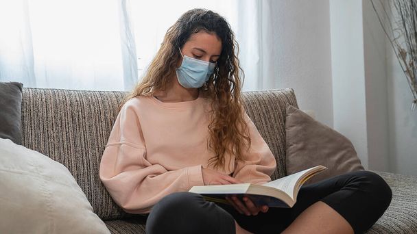 Coronavirus.Adolescente leyendo un libro en casa, protegido contra el coronavirus. Pandemia. Distancia social
 - Foto, imagen